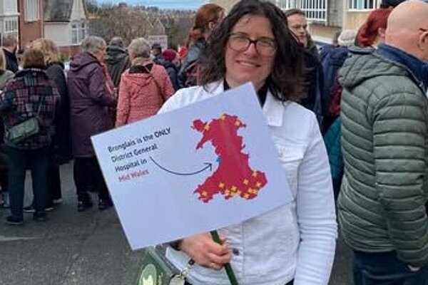 Sandra Jervis at a protest holding a banner saying Save Bronglais Services